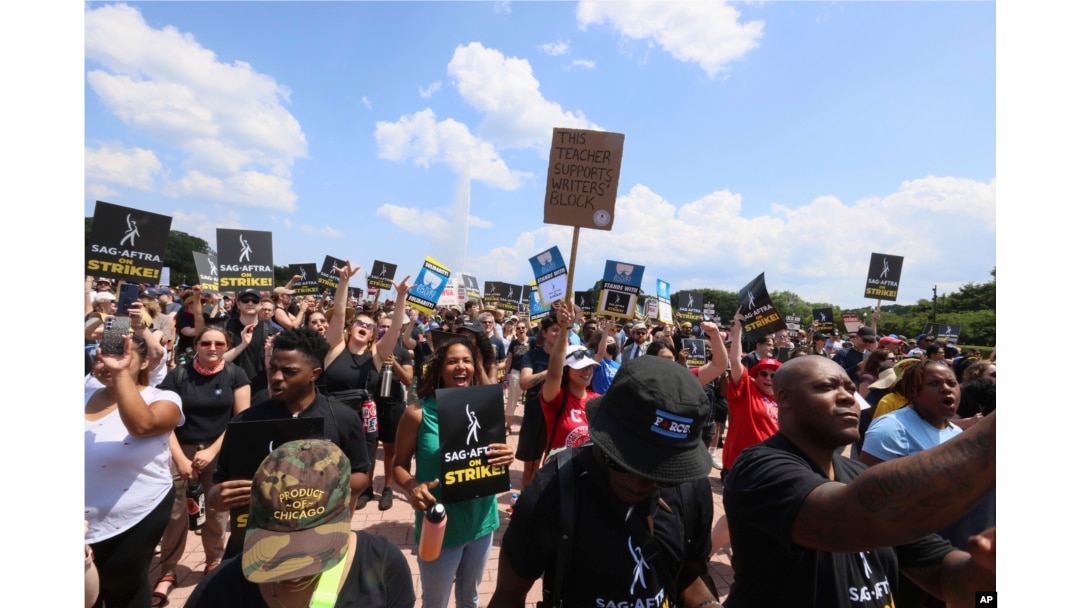 Striking screenwriters and actors hold signs at a rally in Chicago, Thursday, July 20, 2023, as the labor dispute that has halted Hollywood spreads to more cities. (AP Photo/Teresa Crawford)