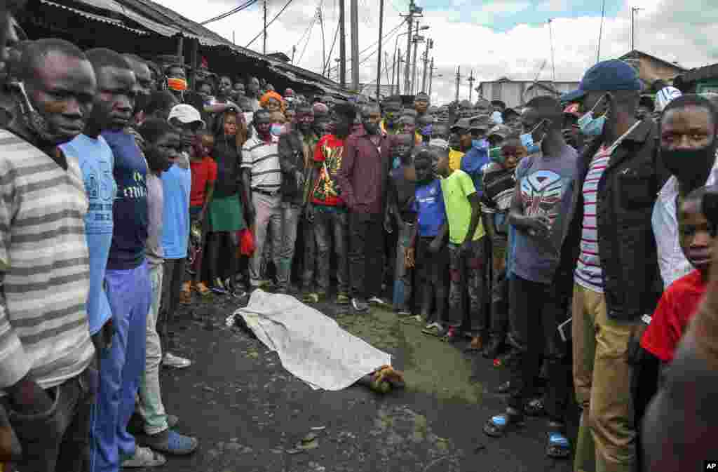 Residents gather around the covered dead body of a man, who they claimed had been beaten by police for being outside during the dusk to dawn curfew, but which could not be independently verified, in the Mathare slum of Nairobi, Kenya.