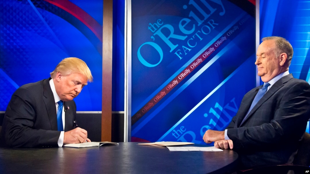 Republican presidential candidate Donald Trump, left, signs his book for Bill O'Reilly, right, during his appearance on Fox's news talk show "The O'Reilly Factor," Nov. 6, 2015, in New York.