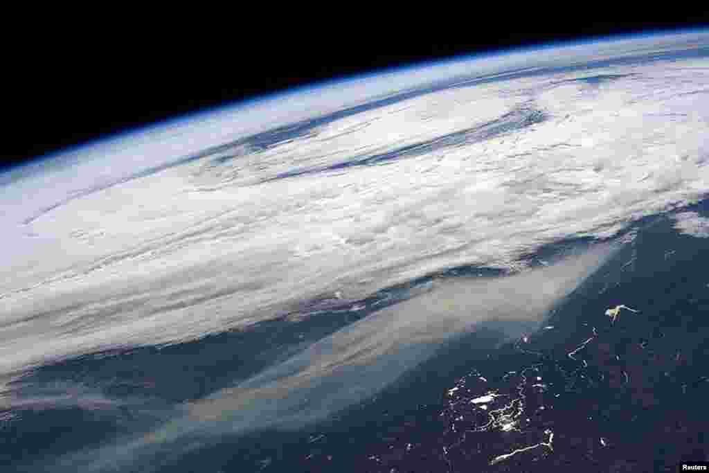 Kepulan asap (bawah) dari kebakaran hutan besar di dan di sekitar Ft. McMurray, Alberta, Kanada tampak dalam gambar yang diambil oleh astronot NASA, Jeff Williams, dari Stasiun Angkasa Internasional.