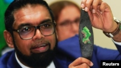 El presidente guyanés Irfaan Ali muestra a la prensa un brazalete con la imagen impresa del Esequibo, luego de reunirse el jueves con su homólogo venezolano Nicolás Maduro en San Vicente y las Granadinas.