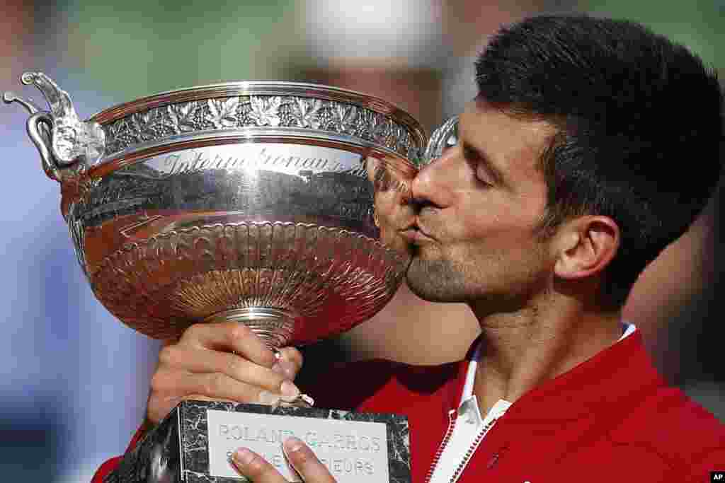 Petenis Serbia, Novak Djokovic mencium trophy setelah menjuarai turnamen Perancis Terbuka di Roland Garros, Paris hari Minggu (5/6).