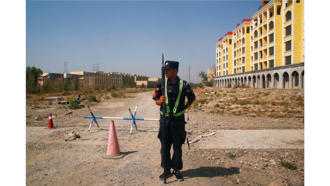 FILE - A Chinese police officer takes his position by the road near what is officially called a vocational education center in Yining in Xinjiang Uighur Autonomous Region, China, Sept. 4, 2018.