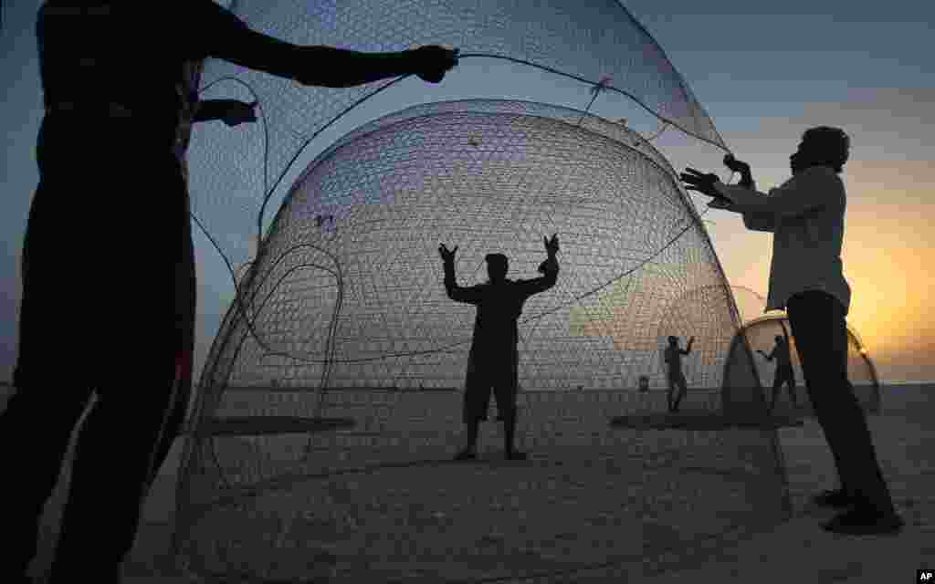 Indian fishermen collect a gargour trap after it was repaired during the sunset of the last day of fishing season at Jumeirah fishing harbor in Dubai, UAE. Most of the fishermen will travel to their home countries before they come back in about three months to start the new fishing season.