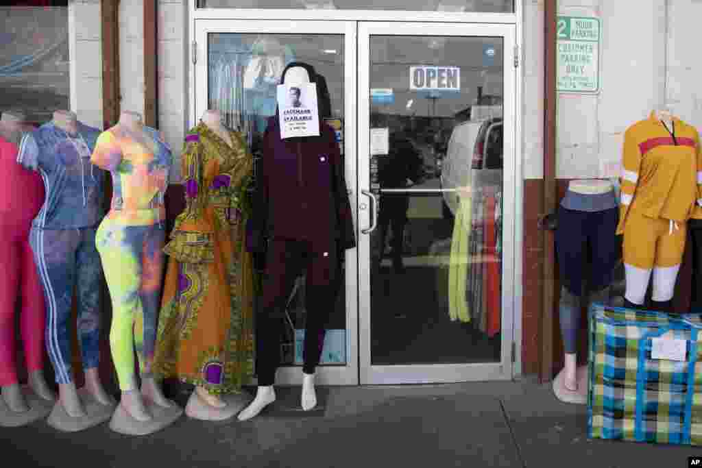 A sign that reads "FACEMASK AVAILABLE" is taped to a mannequin outside Trade Linker International at Union Market in Washington, D.C., March, 17, 2020.
