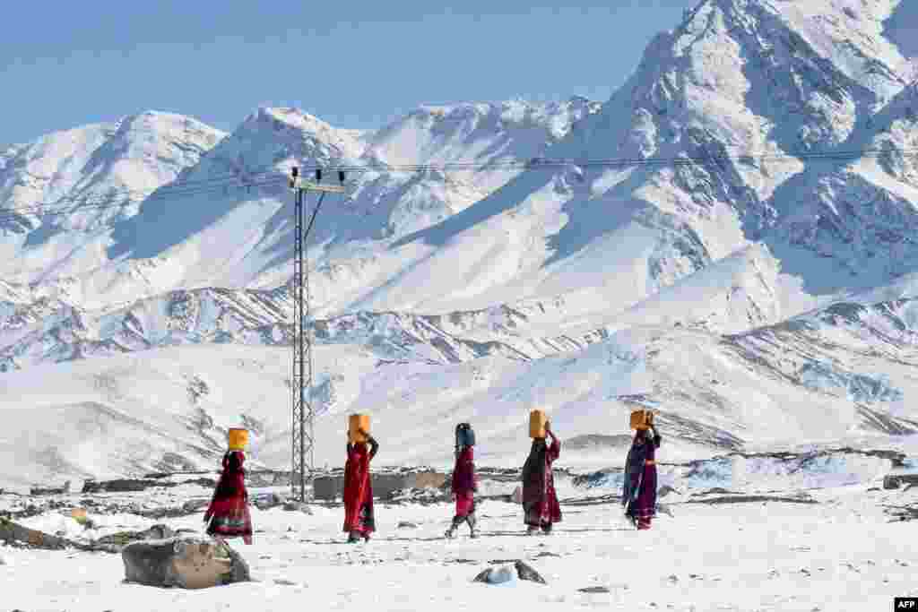 Local residents carry water pots above their heads as they walk back to their homes after heavy snowfall in Khanozai area some 75 kms in northeast of the provincial capital Quetta, Pakistan. Avalanches, flooding and harsh winter weather has killed more than 110 people across Pakistan and Afghanistan in recent days, officials said.
