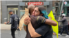 Manifestantes se abrazan en una protesta en Washington, Minnesota, no llevan máscaras y no guardan una distancia social apropiada de protección contra el coronavirus. [Foto: Ronec Suarc, VOA]