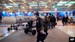 FILE - Visitors look at a cruise missile at a military hardware exhibit, at Imam Khomeini Grand Mosque, in Tehran, Iran, Feb. 3, 2019.