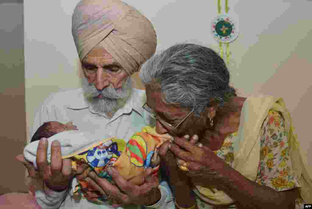 Pasangan suami istri Mohinder Singh Gill, 79 dan istrinya Daljinder Kaur, 70 menggendong bayi lelaki mereka, Arman, di rumahnya di Amritsar. Daljinder Kaur melahirkan anaknya dua bulan yang lalu setelah menjalani perawatan IVF bersama suaminya di klinik kesuburan di negara bagian India utara, Haryana.