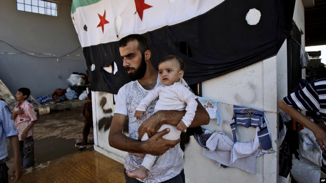A Syrian man, who fled his home due to government shelling, holds his son as they take refuge at Bab Al-Salameh crossing border, hoping to cross to one of the refugee camps in Turkey, near the Syrian town of Azaz, Sept. 12, 2012. 