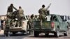 FILE - This photo released Sept 4, 2017, by the Syrian official news agency SANA shows Syrian troops and pro-government gunmen standing on pickup trucks with heavy machine guns mounted on them, in the eastern city of Deir el-Zour, Syria.