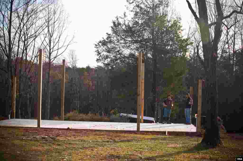 Kevin, the owner, with a family friend as they stand on the base of their future barn. (Alison Klein/VOA)