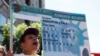ARCHIVO - Una mujer sostiene una réplica de un cartel con la imagen de la tarjeta de residencia de color verde o green card durante una marcha de protesta para exigir una reforma migratoria en Hollywood, Los Ángeles, California, el 5 de octubre de 2013.