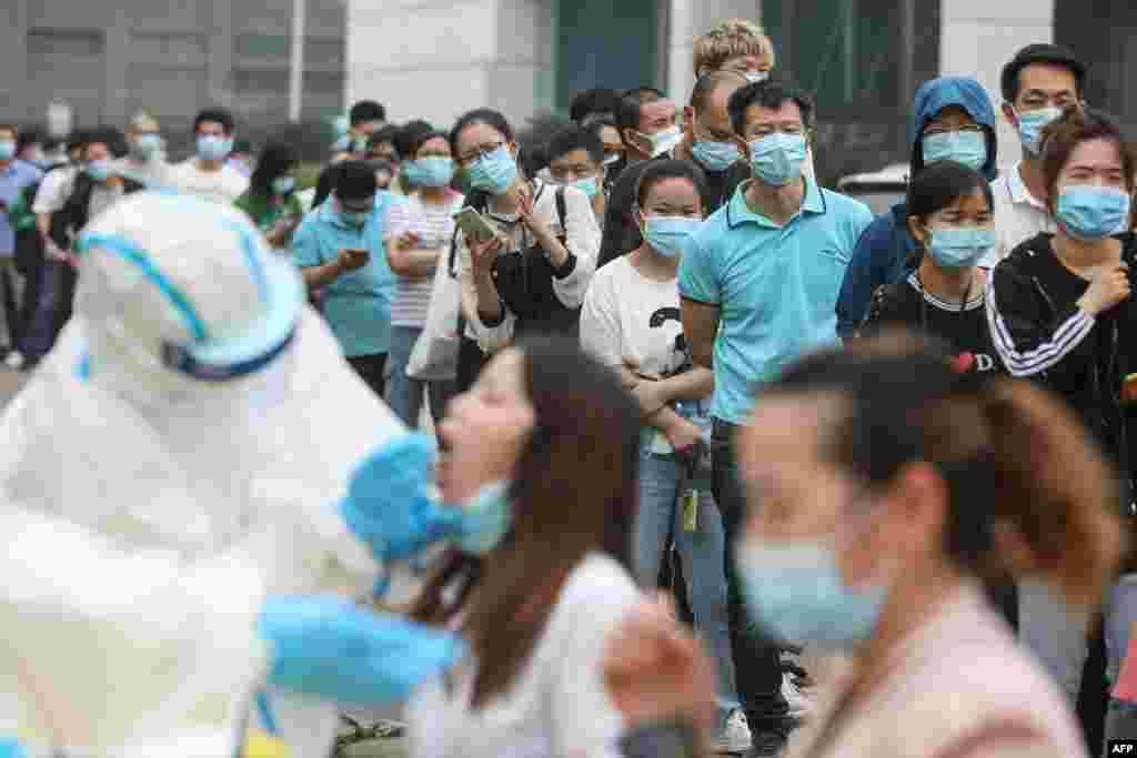 Staff members from the AOC computer monitor factory queue to be tested for the COVID-19 coronavirus in Wuhan, in China's central Hubei province.