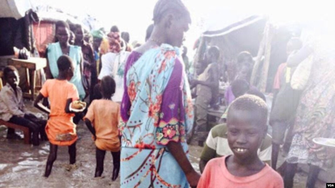 A child stands in floodwaters at a camp for people displaced by violence, Bentiu, South Sudan (G. Joselow/VOA).