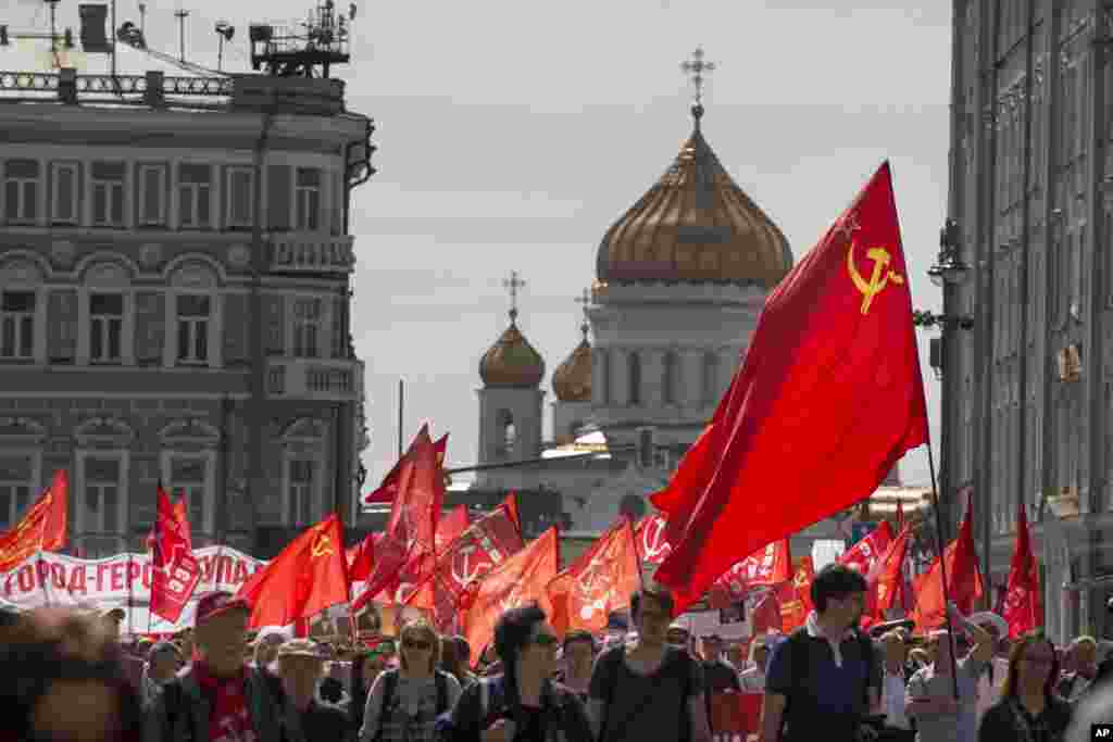 People march with red flags with the Christ the Savior Cathedral in the background during a Communist rally to mark May Day in Moscow, Russia, Monday, May 1, 2017.