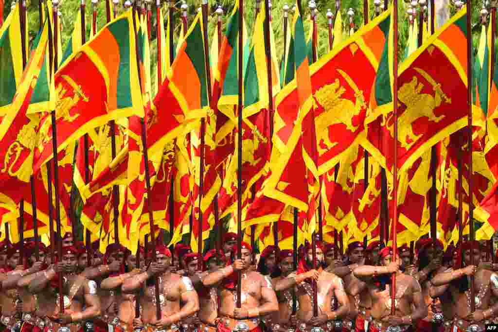 Sri Lankan military personnel march in traditional dress holding national flags during the country's 72nd Independence Day celebrations in Colombo.