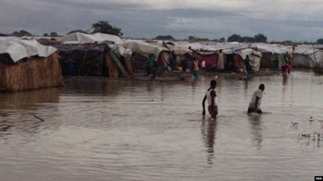 Residents of flooded protection site for people displaced by violence cross waist-high water as part of daily routine, Bentiu, South Sudan (G. Joselow/VOA).