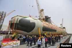 Employees stand near the Indian Navy's first Scorpene submarine before being undocked on April 6 at a naval vessel ship building yard, in Mumbai.