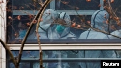 Members of the World Health Organization (WHO) team, tasked with investigating the origins of the coronavirus disease (COVID-19), don personal protection suits during a visit at the Hubei Animal Epidemic Disease Prevention and Control Center in Wuhan, Hub