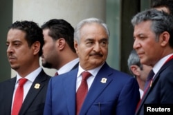 FILE - Khalifa Haftar, center, the military commander who dominates eastern Libya, leaves after an international conference on Libya in Paris, France, May 29, 2018.