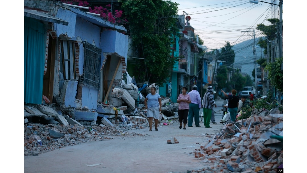 Residents stand next to buildings damaged by a 7.1 earthquake, in Jojutla, Morelos state, Mexico, Sept. 20, 2017.