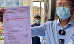 香港新同盟荃灣區議員譚凱邦展示一張香港市民接受中資公司中龍作免費病毒檢測的”知情同意書”，（美國之音湯惠芸攝）