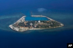 FILE - The Vietnamese-claimed Southwest Cay island in the Spratly island group is seen from a Philippine Air Force C-130 transport plane during the visit to the Philippine-claimed Thitu Island by Defense Secretary Delfin Lorenzana, Armed Forces Chief Gen.