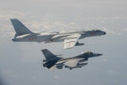 FILE - A Taiwanese F-16 fighter jet flies next to a Chinese H-6 bomber, top, in Taiwan's air defense zone, in this handout photo taken and released Feb. 10, 2020, by Taiwan's Defense Ministry.
