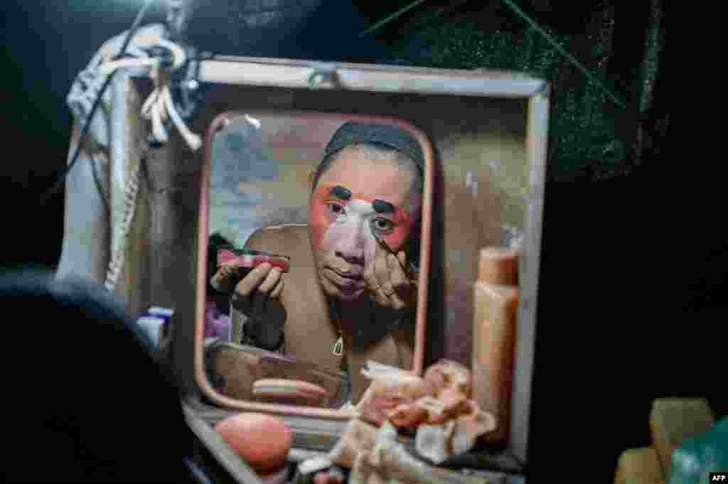 A reflection of an actor applying makeup is seen in the mirror before a Chinese opera performance by Thailand's Sai Bo Hong troupe at a makeshift stage on a street festival in Bangkok, Dec. 28, 2019.