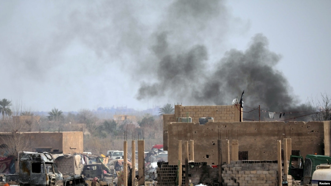 FILE - Islamic State members walk in the last besieged neighborhood in the village of Baghouz, Deir Al Zor province, Syria, March 10, 2019. 