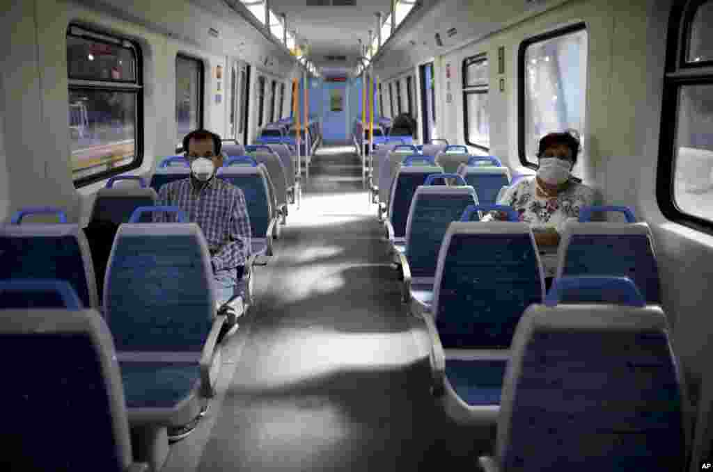 People wearing masks as a precaution against the spread of the new coronavirus ride an empty train in Buenos Aires, Argentina.