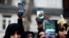 Iranian demonstrators hold up phones with pictures of the late Qassem Soleimani and Iraqi militia commander Abu Mahdi al-Muhandis, who were killed in an airstrike at Baghdad airport, in front of the U.N. office in Tehran, Iran, Jan. 3, 2020.