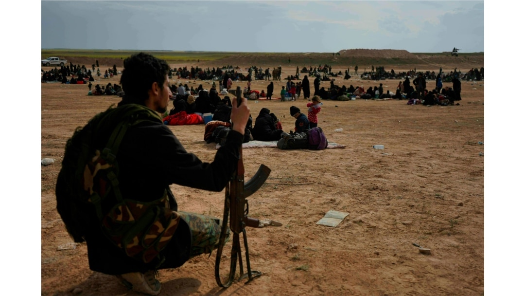 FILE -- A member of U.S.-backed Syrian Democratic Forces (SDF) watches over people who were evacuated out of the last territory held by Islamic State militants, outside Baghouz, Syria, March 5, 2019.