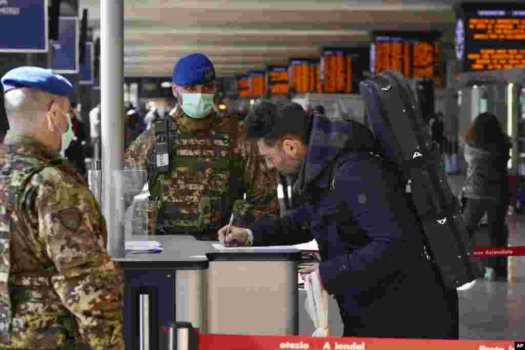 A traveler fills out a form at a check point set up by border police inside Rome's Termini train station, Italy. The government extended a coronavirus containment order previously limited to the country’s north to the rest of the country, with soldiers and police enforcing bans.