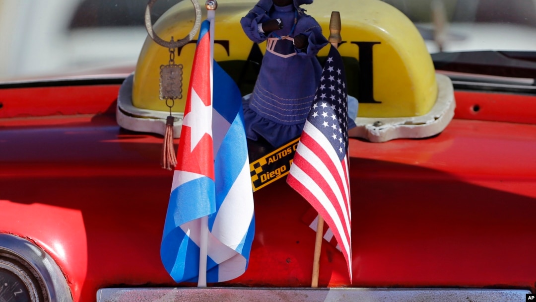 The stars and stripes and the Cuban national flag are placed together on the dashboard of a vintage American convertible in Havana, Cuba, Feb. 18, 2016.