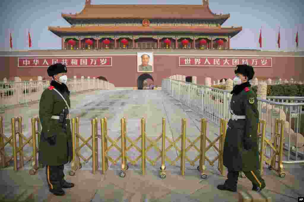Paramilitary police wear face masks as they stand guard at Tiananmen Gate adjacent to Tiananmen Square in Beijing, China.