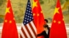 FILE - Chinese staffers adjust U.S. and Chinese flags before a session of negotiations between U.S. and Chinese trade representatives, at the Diaoyutai State Guesthouse, in Beijing, China, Feb. 14, 2019.
