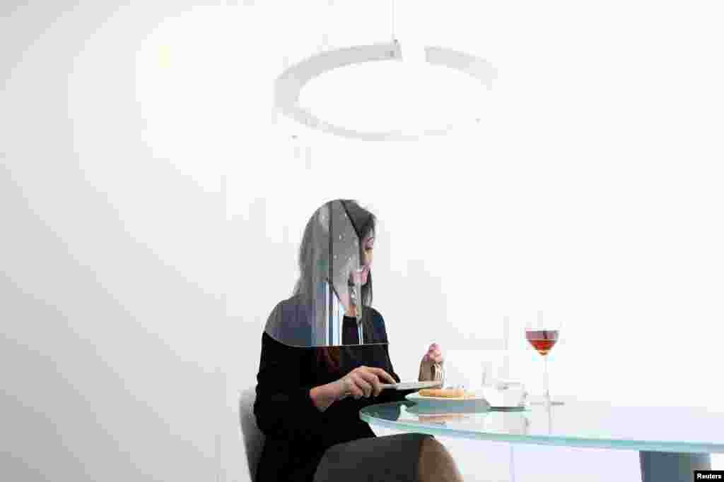 A woman poses under a Plex'Eat prototype plexiglas bubble by designer Christophe Gernigon which surrounds diners to protect them from the novel coronavirus during a presentation in Cormeilles-en-Parisis, near Paris, France.