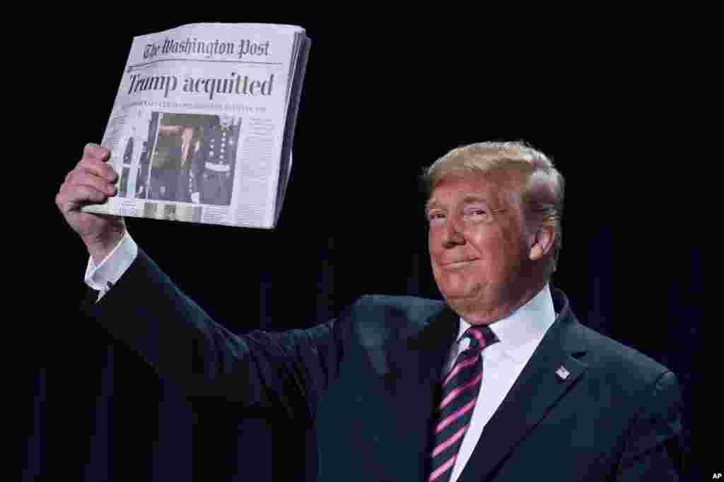 President Donald Trump holds up a newspaper with the headline that reads "Trump acquitted" during the 68th annual National Prayer Breakfast, at the Washington Hilton in Washington, D.C.