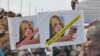 A protester holds up signs protesting against UNMISS head Hilde Johnson at a rally in Juba after South Sudanese government forces found weapons in a UN overland shipment.