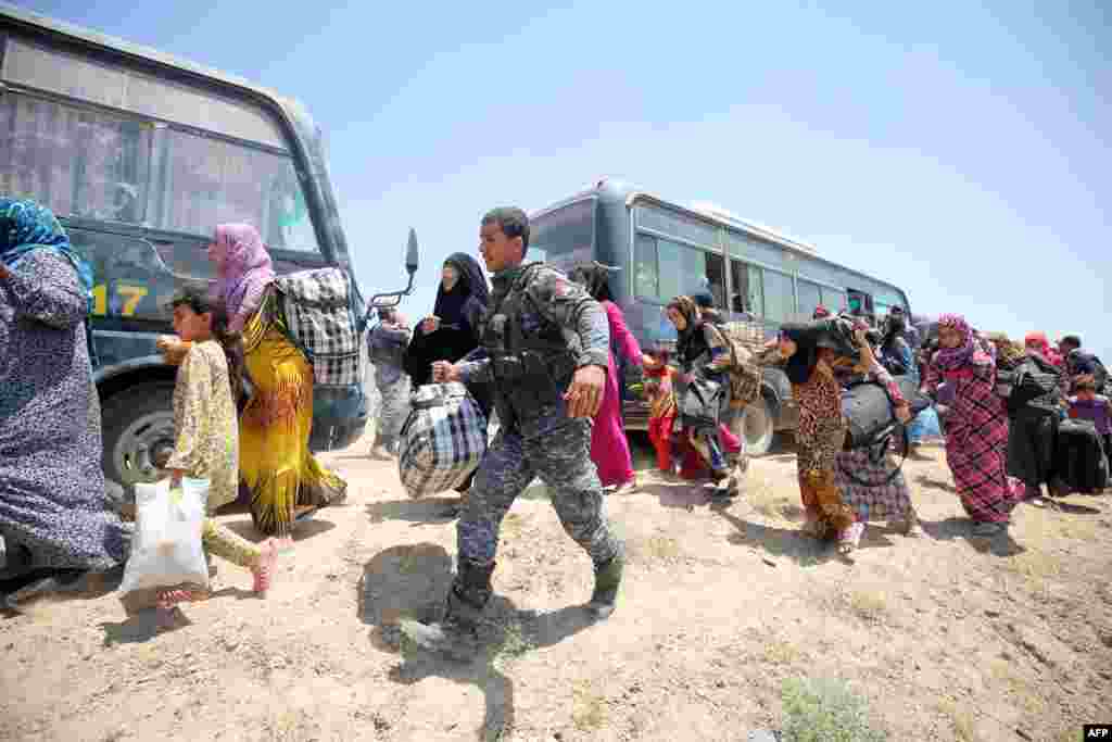 Tentara Irak membantu keluarga-keluarga dekat desa al-Sejar di provinsi Anbar yang melarikan diri dari Fallujah (27/5), di tengah operasi besar untuk merebut kota itu dari tangan Negara Islam (ISIS). (AFP/Ahmad al-Rubaye)