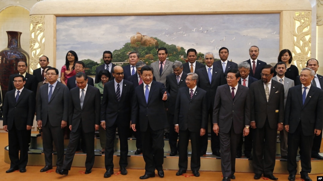 FILE - Chinese President Xi Jinping, center, shows the way to the guests who attended the signing ceremony of the Asian Infrastructure Investment Bank at the Great Hall of the People in Beijing, Oct. 24, 2014.