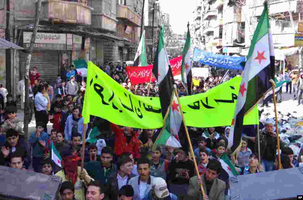 Anti-Syrian regime protesters hold banners and flags during a demonstration in the neighborhood of Bustan Al-Qasr in Aleppo, March 29, 2013.