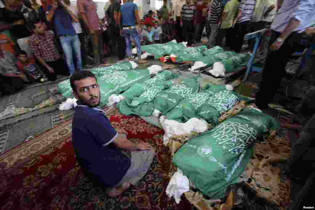 A man sits next to the bodies of Palestinians from the Abu Jama'e family, who medics said were killed in an Israeli air strike that destroyed their house, during their funeral at a mosque, in Khan Younis, in the southern Gaza Strip, July 21, 2014.