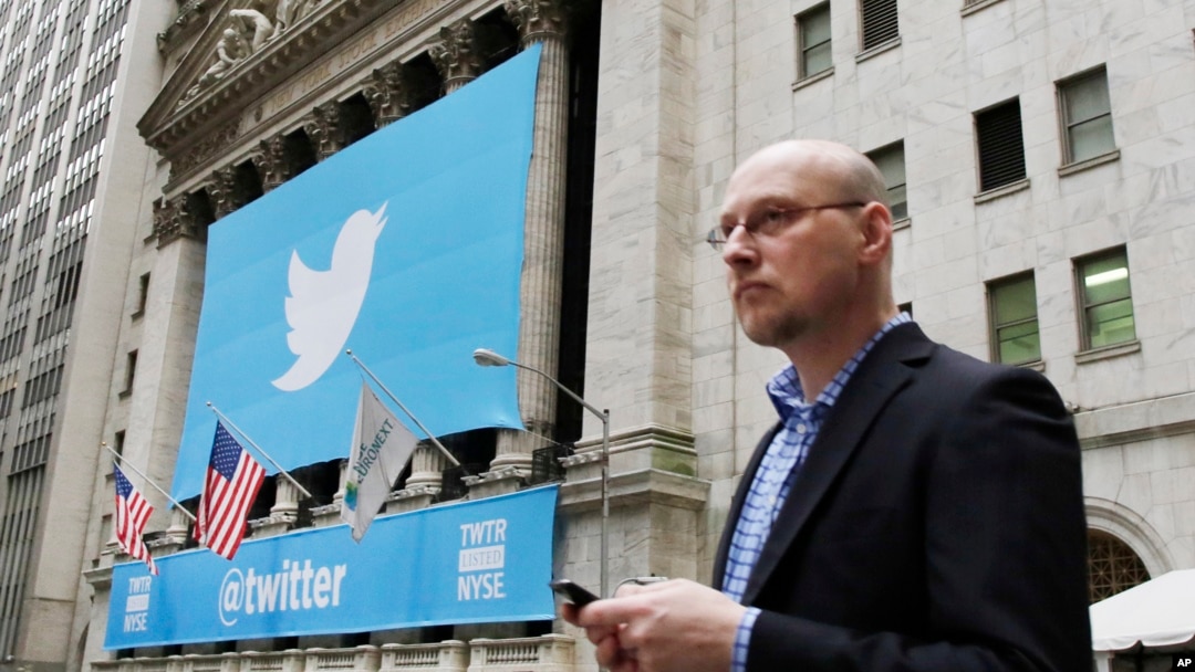 A man uses a mobile phone as he walks past the New York Stock Exchange ahead of Twitter IPO on November 7, 2013, in New York. 