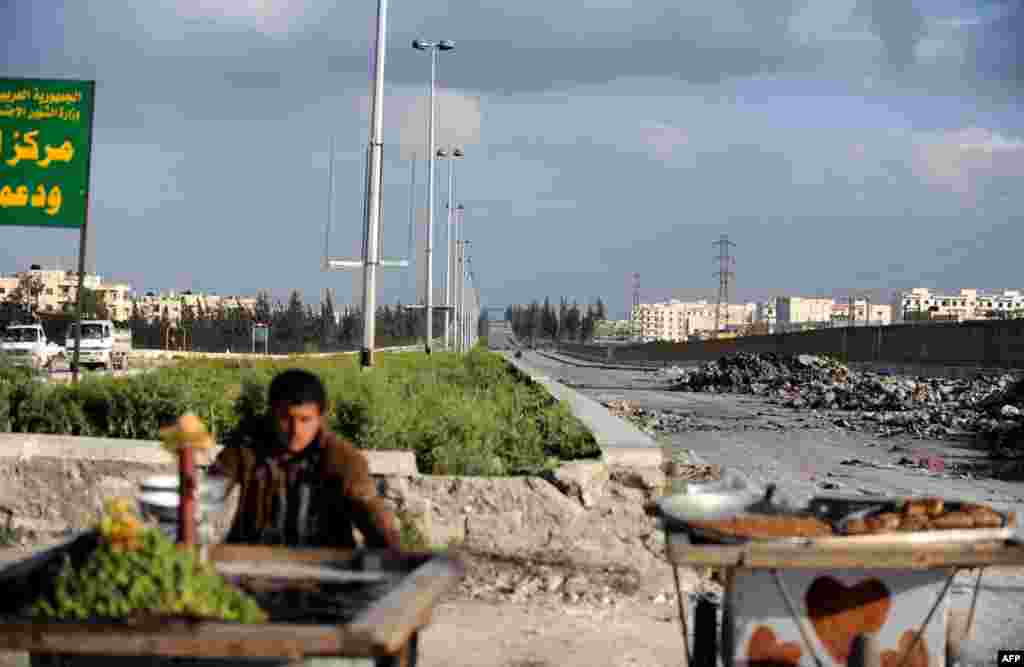 A Syrian man pushes a cart past the road leading to Aleppo airport, March 28, 2013.