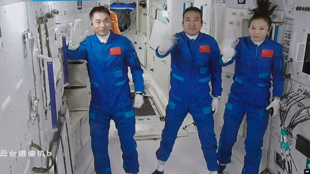 A screen grab taken at Beijing Aerospace Control Center in Beijing, China, Oct. 16, 2021, and released by Xinhua News Agency, shows three Chinese astronauts waving after they entered China's Tiangong space station core module Tianhe. 