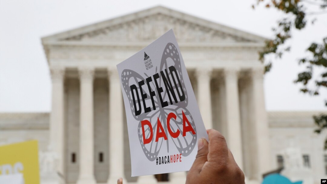 FILE - A sign is held aloft as people rally outside the Supreme Court in support of the Deferred Action for Child Arrivals program, Nov. 12, 2019, in Washington.