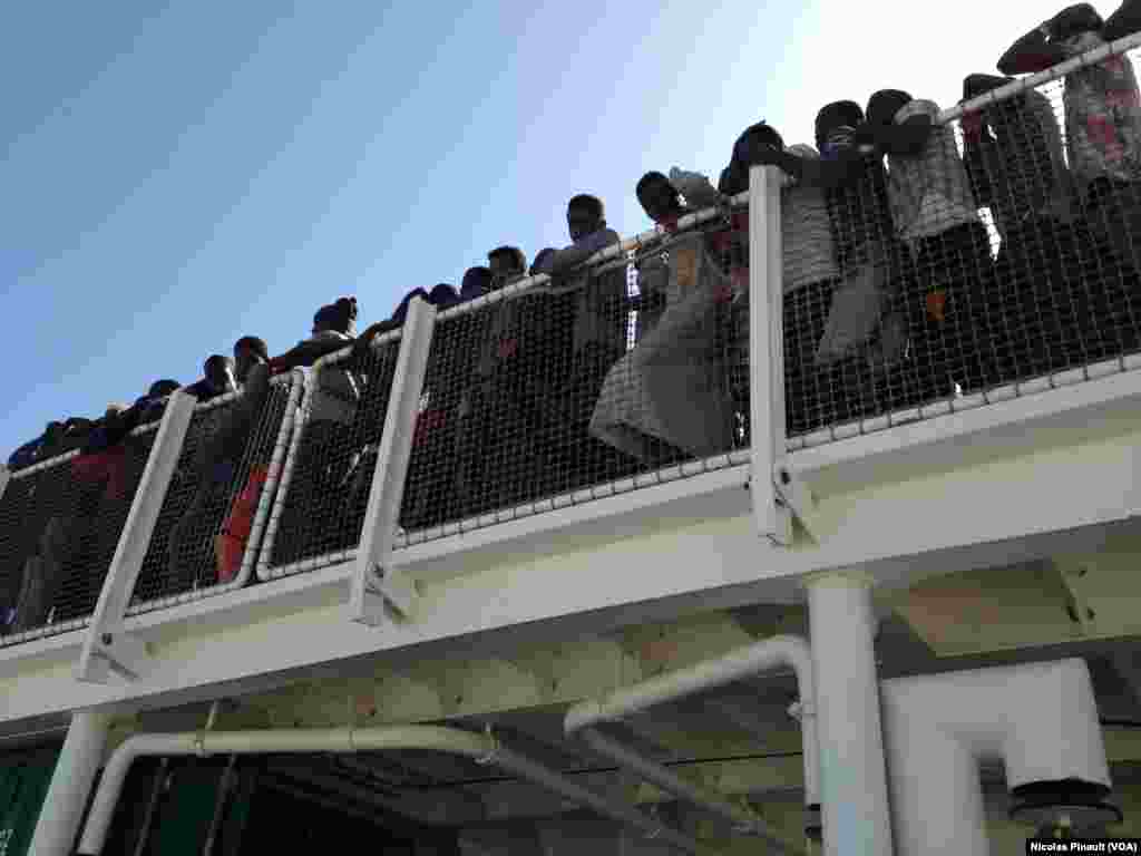 Migrants wait to disembark the Spanish vessel which rescued them in the Mediterranean, as they arrive in Pozzallo.